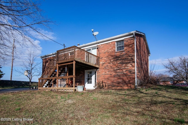 rear view of property with brick siding, a wooden deck, and a lawn