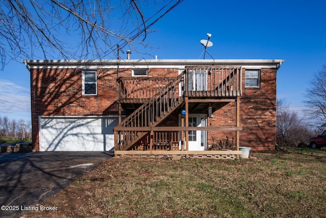 back of house with a garage, aphalt driveway, stairway, and brick siding
