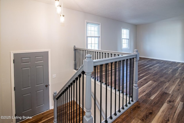 stairway featuring a textured ceiling, wood finished floors, and baseboards