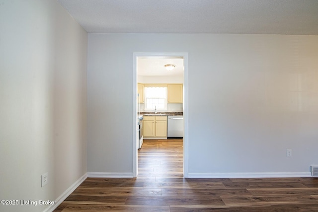 interior space with baseboards, dark wood-style flooring, a sink, and visible vents