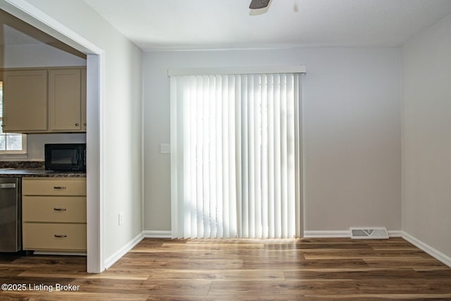 unfurnished dining area featuring visible vents, baseboards, a ceiling fan, and wood finished floors