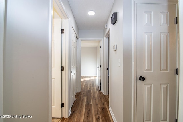 hallway with baseboards and wood finished floors