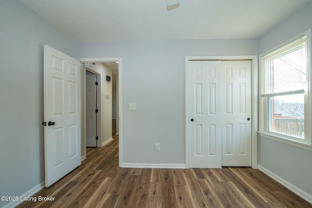 unfurnished bedroom with a closet, baseboards, and wood finished floors