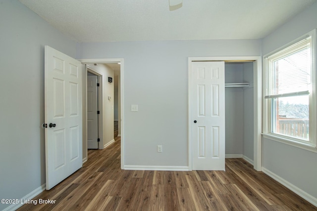 unfurnished bedroom featuring wood finished floors, baseboards, and multiple windows