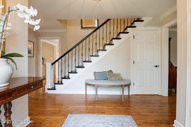 staircase with crown molding, baseboards, and wood finished floors