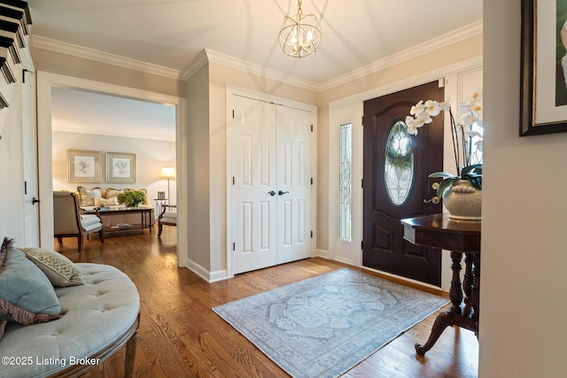 foyer featuring crown molding, baseboards, an inviting chandelier, and wood finished floors