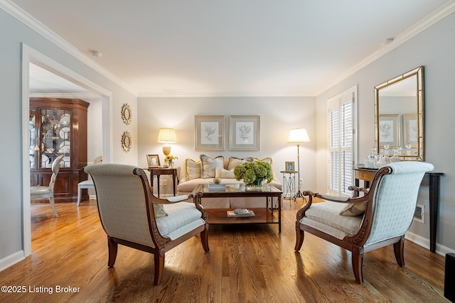 living area with baseboards, ornamental molding, and wood finished floors