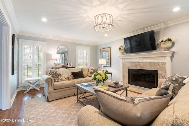 living room featuring wood finished floors, a fireplace, ornamental molding, and baseboards
