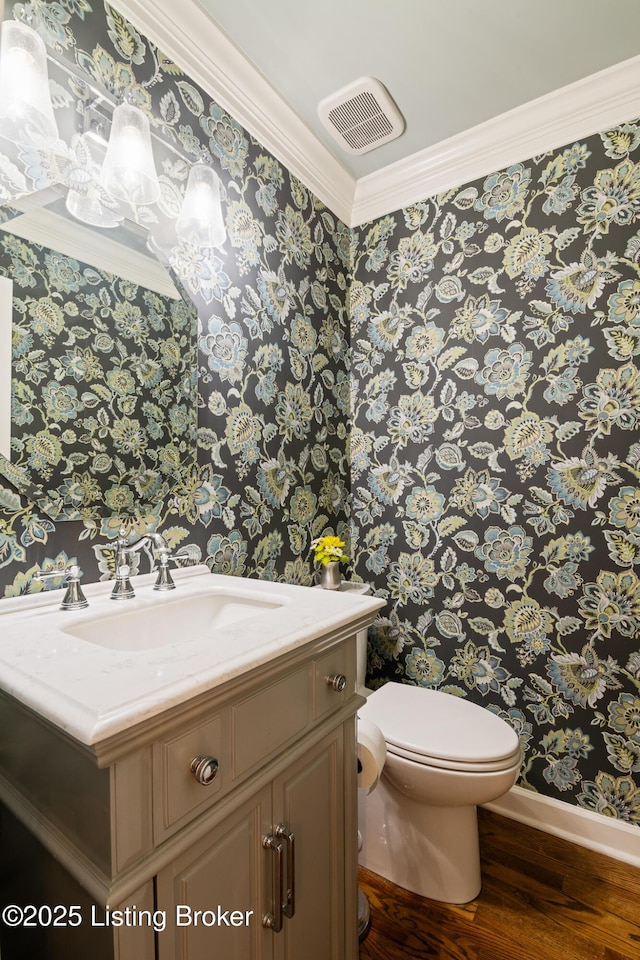 half bath featuring visible vents, baseboards, toilet, wood finished floors, and wallpapered walls