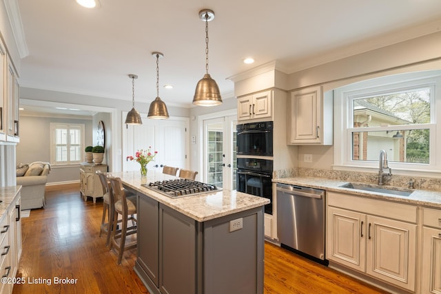 kitchen with light stone countertops, a center island, appliances with stainless steel finishes, dark wood-style flooring, and a sink