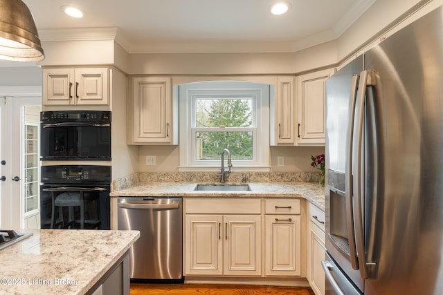kitchen featuring stainless steel appliances, ornamental molding, a sink, and light stone counters