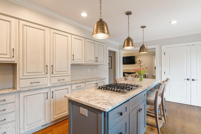 kitchen featuring ornamental molding, recessed lighting, a center island, pendant lighting, and stainless steel gas stovetop