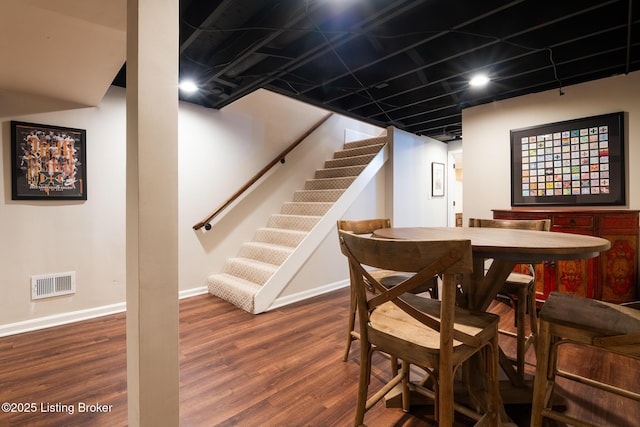 dining space featuring wood finished floors, baseboards, visible vents, and stairway