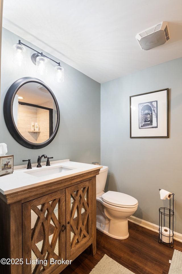 bathroom featuring visible vents, baseboards, toilet, vanity, and wood finished floors