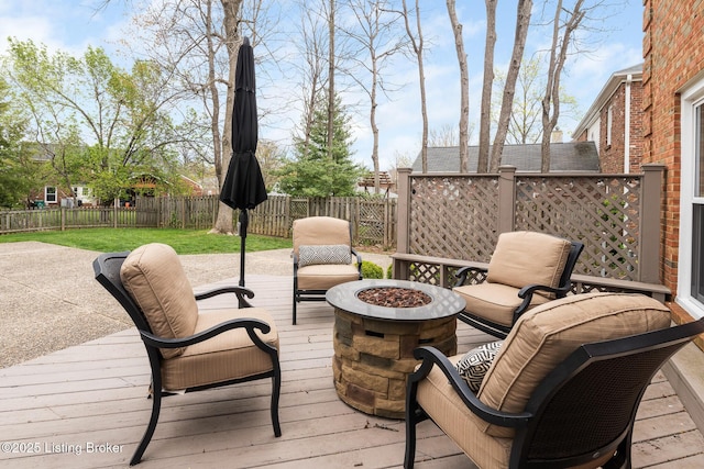 wooden terrace with a fenced backyard and a fire pit