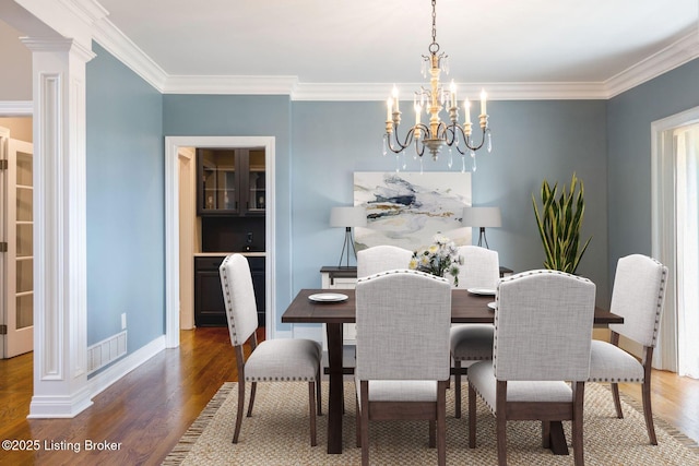 dining space with visible vents, ornamental molding, wood finished floors, and an inviting chandelier