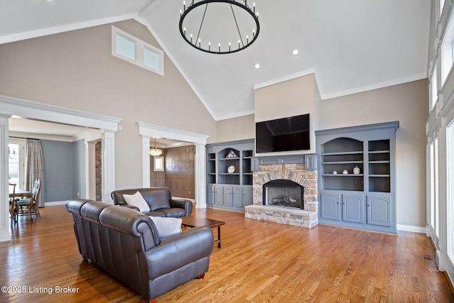 living area featuring an inviting chandelier, high vaulted ceiling, a fireplace, and decorative columns
