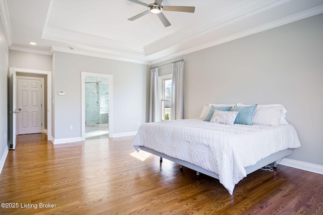 bedroom with baseboards, a tray ceiling, and wood finished floors