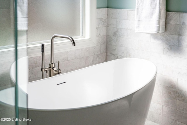 bathroom with a freestanding tub and tile walls