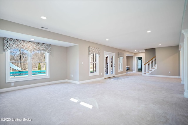 unfurnished living room featuring stairway, baseboards, and light colored carpet
