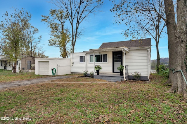 view of front of property featuring an outdoor structure, a front yard, and a garage