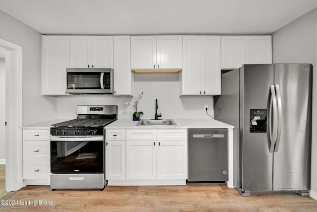 kitchen with white cabinets, light countertops, stainless steel appliances, and a sink