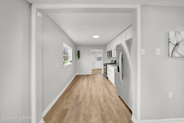 corridor featuring light wood finished floors and baseboards