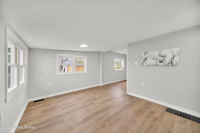 spare room with baseboards, light wood-style flooring, and visible vents