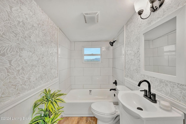 bathroom featuring toilet, wainscoting, visible vents, wallpapered walls, and wood finished floors