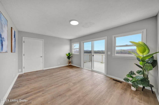 empty room with light wood-style flooring, visible vents, baseboards, and a water view