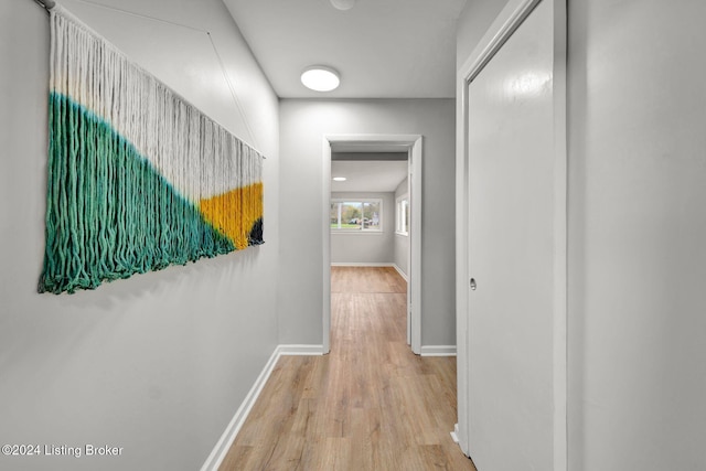 corridor with wood finished floors and baseboards