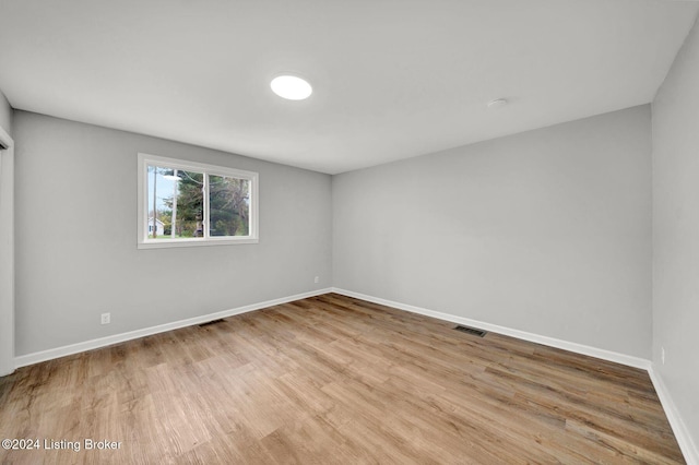 unfurnished room with baseboards, wood finished floors, and visible vents
