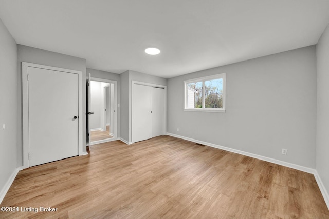 unfurnished bedroom with baseboards, light wood finished floors, and a closet