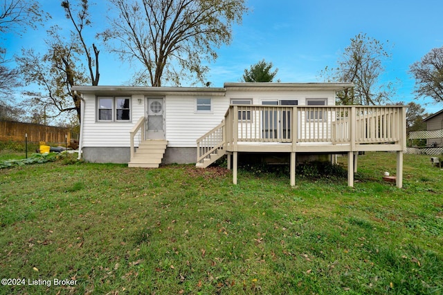 rear view of property featuring a lawn, entry steps, and a deck
