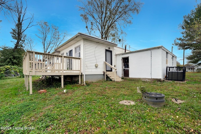 back of property featuring entry steps, a lawn, and a deck