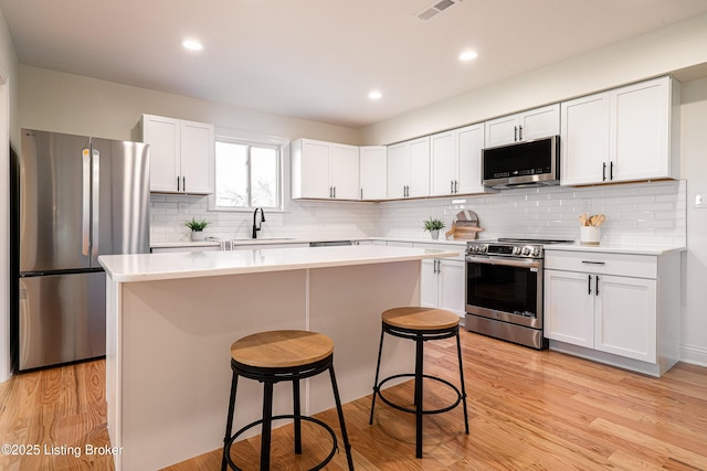 kitchen with light countertops, appliances with stainless steel finishes, a sink, and a kitchen breakfast bar