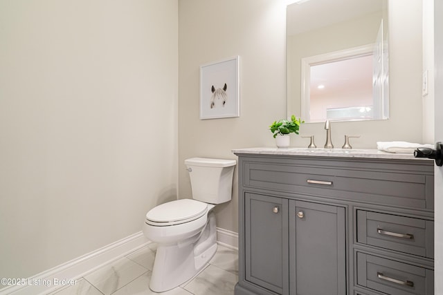half bath featuring vanity, baseboards, and toilet