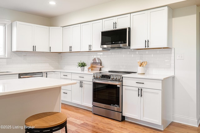 kitchen featuring light wood-type flooring, recessed lighting, light countertops, white cabinetry, and appliances with stainless steel finishes