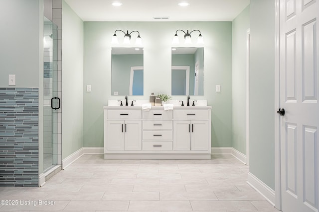 full bath featuring visible vents, baseboards, a shower stall, and double vanity