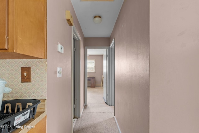 hallway with light colored carpet and baseboards