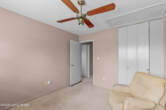 sitting room with light carpet, baseboards, attic access, and a ceiling fan