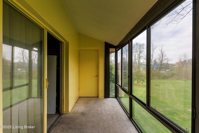 unfurnished sunroom featuring carpet and lofted ceiling