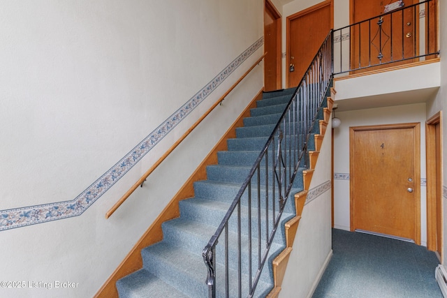 stairs with carpet floors, baseboards, and a baseboard heating unit
