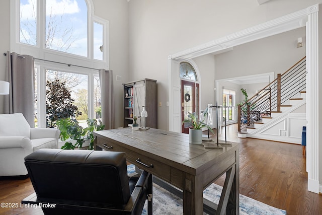 home office featuring wood finished floors and a towering ceiling