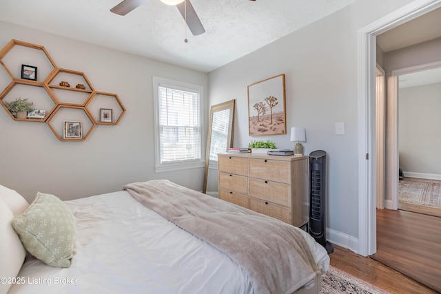bedroom with ceiling fan, baseboards, and wood finished floors