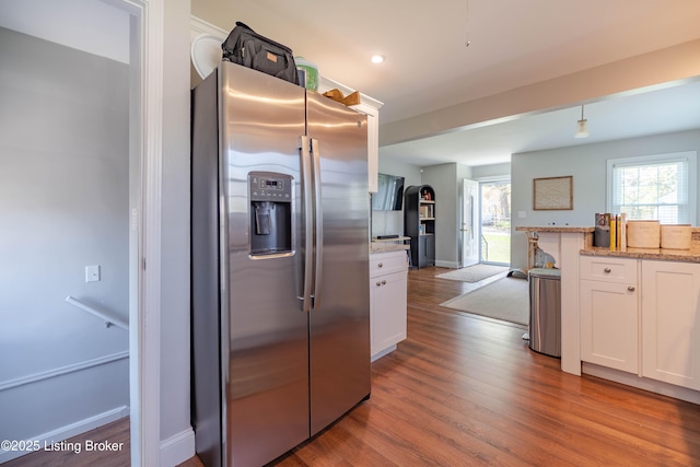 kitchen featuring stainless steel fridge with ice dispenser, light stone countertops, white cabinetry, and wood finished floors