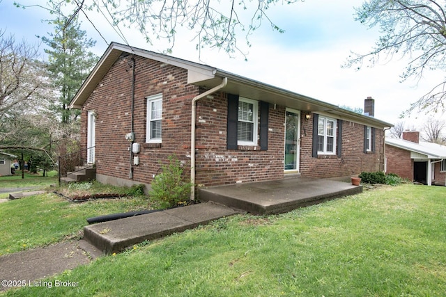 view of front facade featuring a chimney, a front lawn, and brick siding