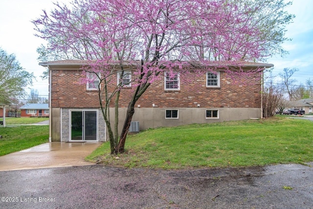 view of side of home with a yard, brick siding, and cooling unit