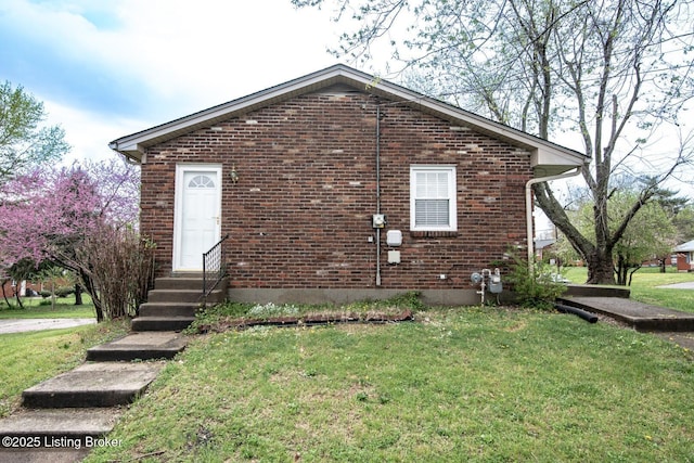 view of property exterior with entry steps, a yard, and brick siding