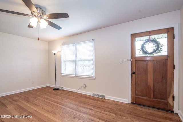 foyer with wood finished floors, baseboards, and visible vents